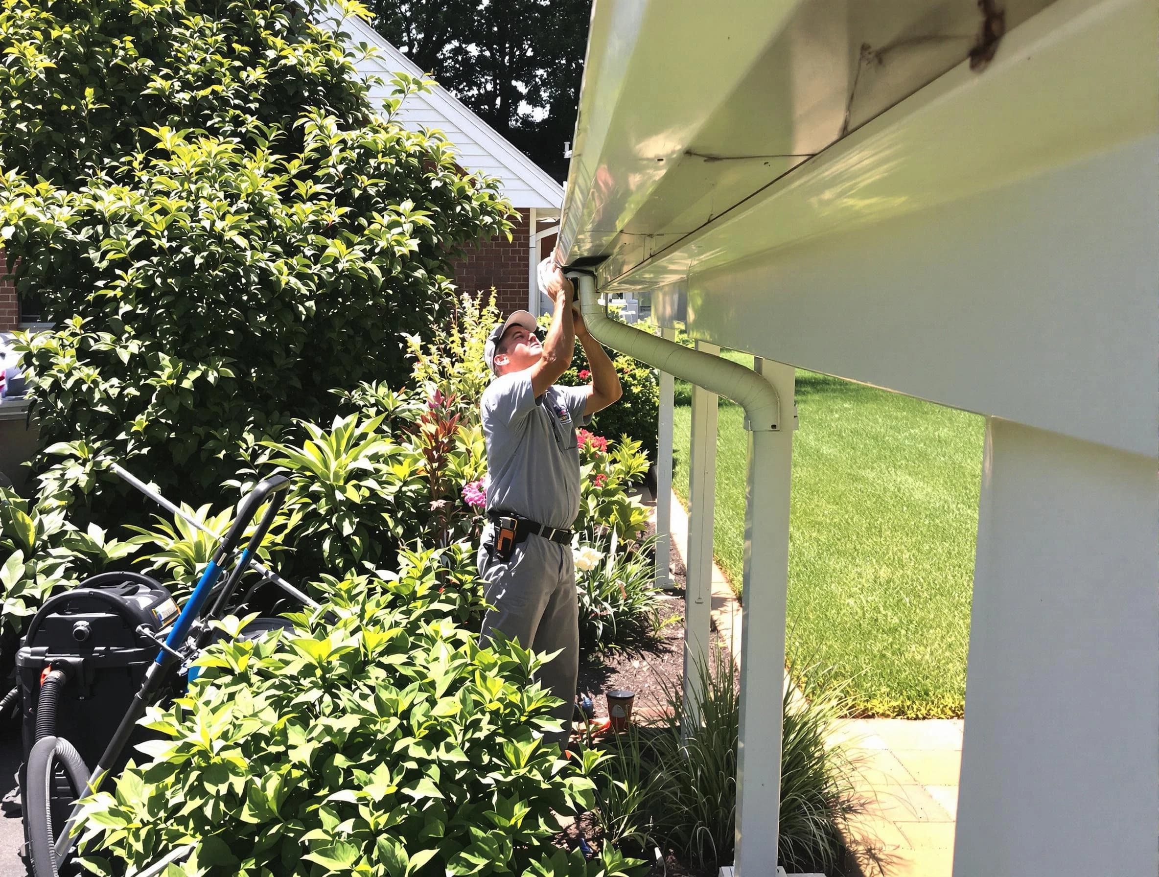 Technician flushing a blockage from a downspout in Beachwood, OH